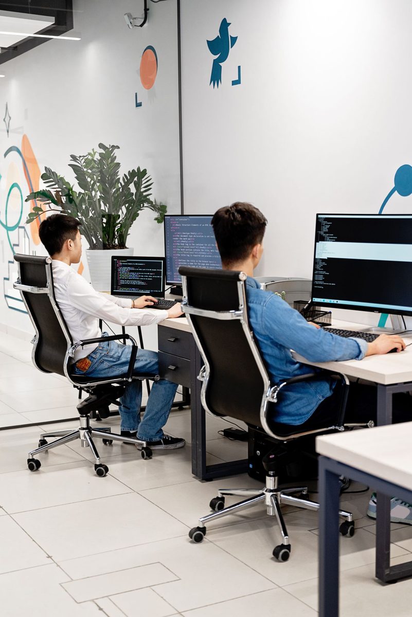 Dos programadores trabajando con código en una oficina luminosa
